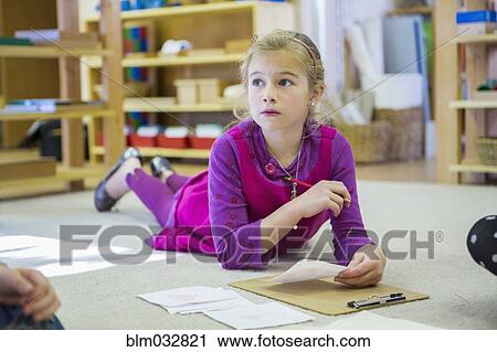 Stock Image - Caucasian girl thinking in classroom. Fotosearch