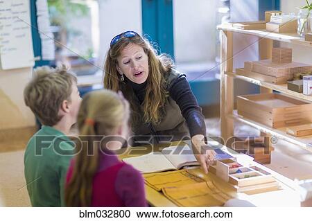 Caucasian Montessori teacher helping students in classroom View Large Photo Image Stock Image - Caucasian Montessori teacher helping students in classroom. Fotosearch