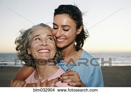 Picture - Caucasian mother and daughter hugging at beach. Fotosearch