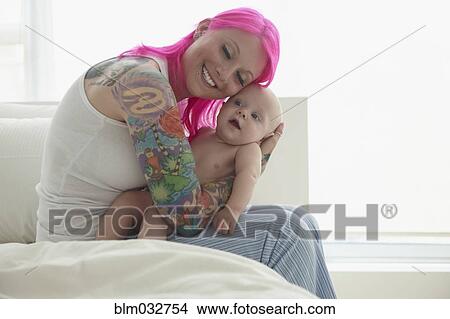 Caucasian mother with pink hair and tattoos cradling baby View Large Photo Image Picture - Caucasian mother with pink hair and tattoos cradling baby. Fotosearch