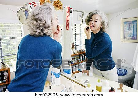 Stock Photography - Caucasian woman applying makeup in mirror. Fotosearch