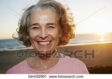 Stock Image - Caucasian woman smiling at beach. Fotosearch
