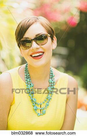Stock Photo - Caucasian woman wearing sunglasses and necklace outdoors. Fotosearch