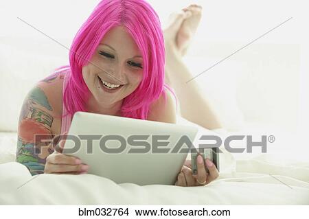 Caucasian woman with pink hair and tattoos shopping online View Large Photo Image Picture - Caucasian woman with pink hair and tattoos shopping online. Fotosearch