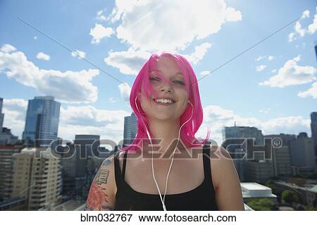 Caucasian woman with pink hair and tattoos listening to earbuds in city View Large Photo Image Stock Photo - Caucasian woman with pink hair and tattoos listening to earbuds in city. Fotosearch