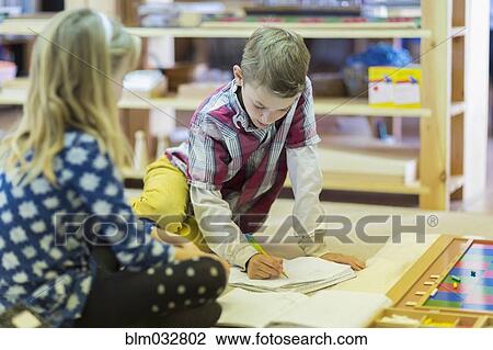 Stock Image - Children writing in classroom. Fotosearch