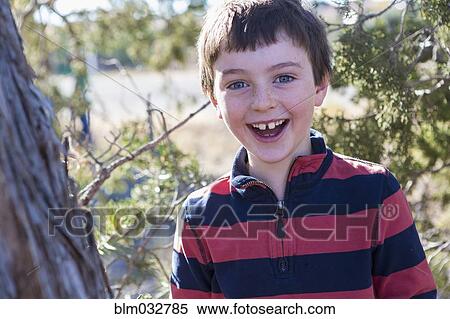 Close up of Caucasian boy smiling near tree View Large Photo Image Stock Photography - Close up of Caucasian boy smiling near tree. Fotosearch