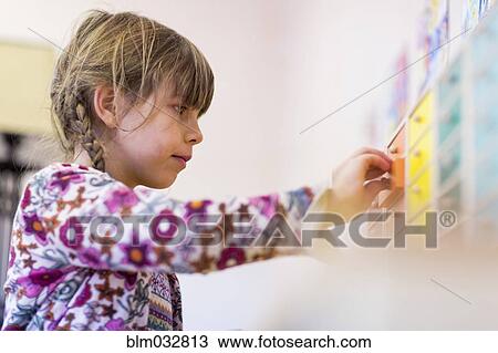 Stock Image - Close up of mixed race girl opening drawer in classroom. Fotosearch