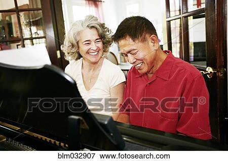 Couple playing piano together in living room View Large Photo Image Stock Photo - Couple playing piano together in living room. Fotosearch