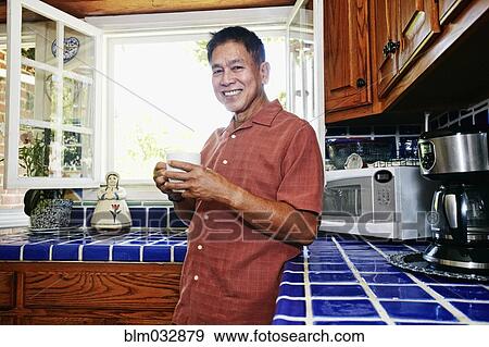 Filipino man drinking cup of coffee in kitchen View Large Photo Image Stock Photo - Filipino man drinking cup of coffee in kitchen. Fotosearch