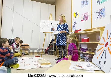 Stock Image - Girl giving presentation to classmates. Fotosearch