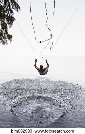 Man jumping from rope swing into lake View Large Photo Image Stock Image - Man jumping from rope swing into lake. Fotosearch