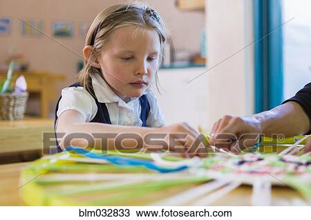 Stock Image - Montessori teacher helping student in classroom. Fotosearch