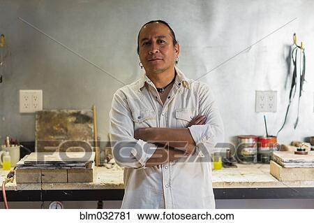 Stock Image - Native American jeweler standing in studio. Fotosearch