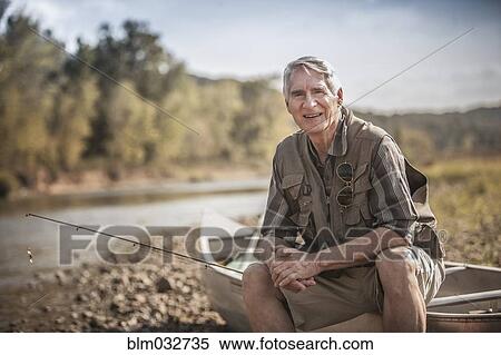 Stock Photography - Older Caucasian man holding fishing rod near river. Fotosearch