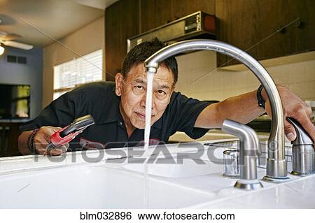 Pacific Islander plumber examining sink in kitchen View Large Photo Image Stock Photograph - Pacific Islander plumber examining sink in kitchen. Fotosearch