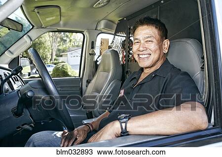 Stock Image - Pacific Islander plumber smiling in van. Fotosearch