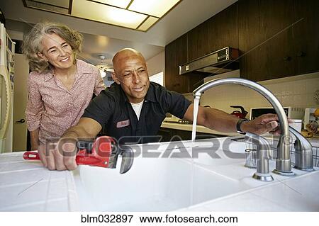 Stock Photo - Plumber testing sink for woman in kitchen. Fotosearch