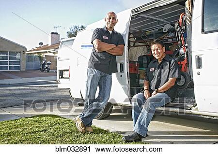 Stock Image - Plumbers smiling in van. Fotosearch