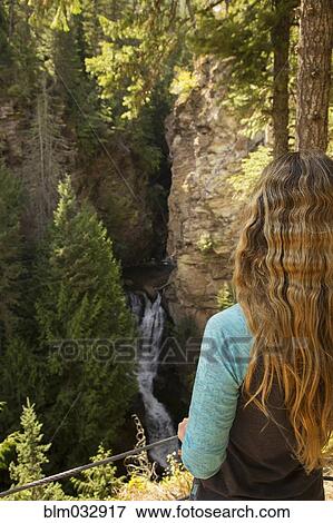 Woman admiring scenic waterfall and cliffs View Large Photo Image Stock Photo - Woman admiring scenic waterfall and cliffs. Fotosearch