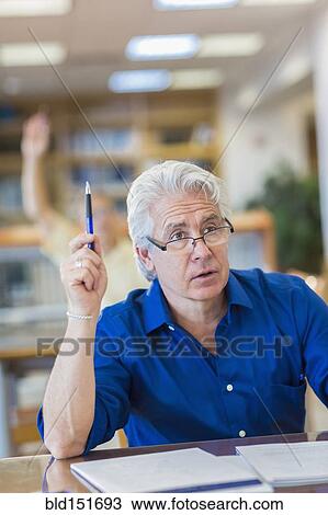 Stock Image - Adult student raising his hand in class. Fotosearch