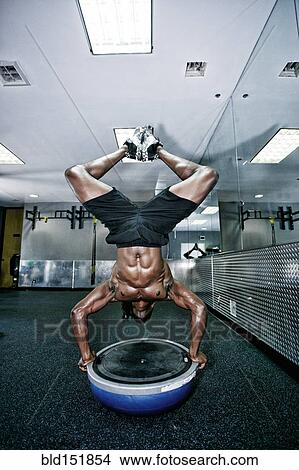 Picture - African American man doing handstand in gym. Fotosearch