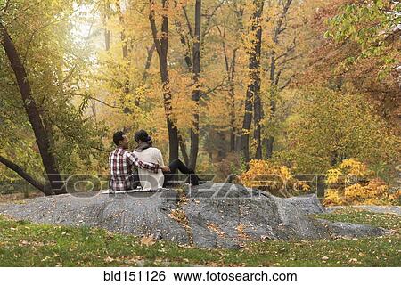 Stock Photograph - Asian couple hugging on rock in park. Fotosearch