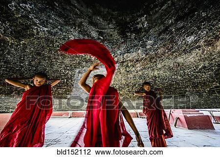 Stock Image - "Asian monks dancing in historic temple, Mingun, Mandalay, Myanmar". Fotosearch