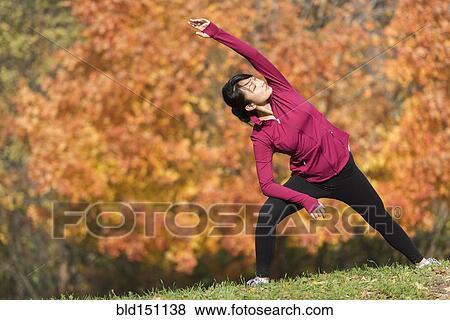 Stock Photo - Asian runner stretching in park. Fotosearch