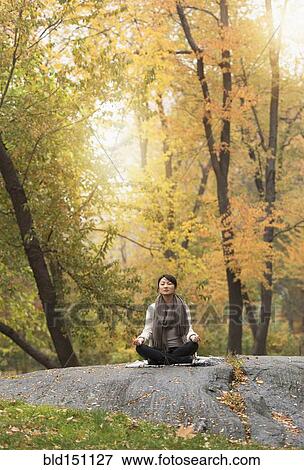 Asian woman meditating on rock in park View Large Photo Image Stock Photo - Asian woman meditating on rock in park. Fotosearch