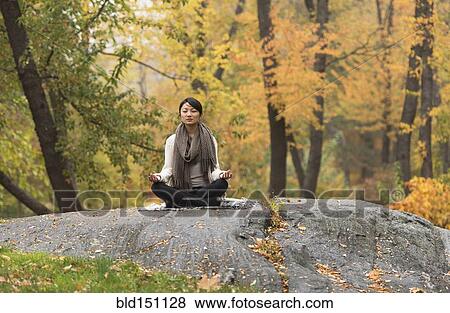 Asian woman meditating on rock in park View Large Photo Image Stock Photo - Asian woman meditating on rock in park. Fotosearch