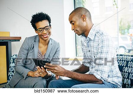 Stock Photo - Black business people using digital tablet in office lobby. Fotosearch