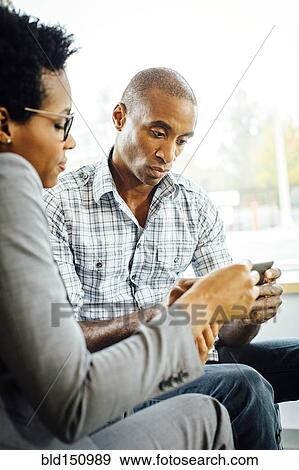 Stock Photo - Black business people using digital tablet in office lobby. Fotosearch