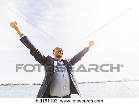 Black businessman cheering with arms outstretched outdoors View Large Photo Image Stock Image - Black businessman cheering with arms outstretched outdoors. Fotosearch