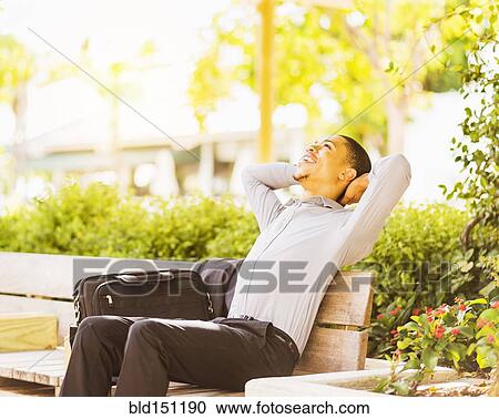 Black businessman relaxing on bench outdoors View Large Photo Image Stock Image - Black businessman relaxing on bench outdoors. Fotosearch