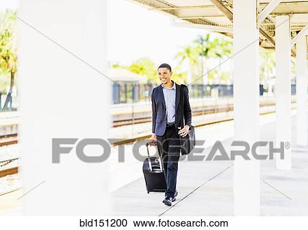 Black businessman rolling luggage on train platform View Large Photo Image Stock Image - Black businessman rolling luggage on train platform. Fotosearch