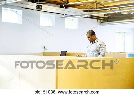Black businessman standing in office cubicle View Large Photo Image Stock Photograph - Black businessman standing in office cubicle. Fotosearch