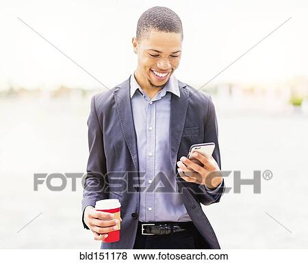 Stock Photo - Black businessman using cell phone outdoors. Fotosearch