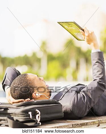 Picture - Black businessman using digital tablet outdoors. Fotosearch