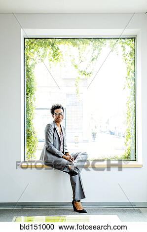 Stock Image - Black businesswoman smiling in office window. Fotosearch