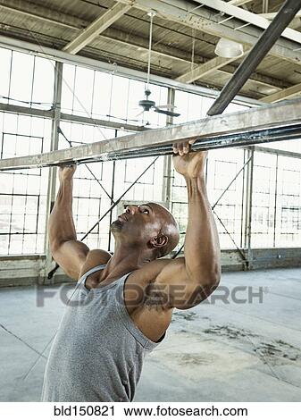 Black man doing pull-ups in warehouse View Large Photo Image Stock Image - Black man doing pull-ups in warehouse. Fotosearch