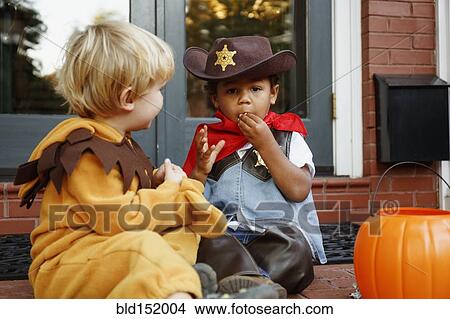 Boys in costumes eating Halloween candy View Large Photo Image Picture - Boys in costumes eating Halloween candy. Fotosearch