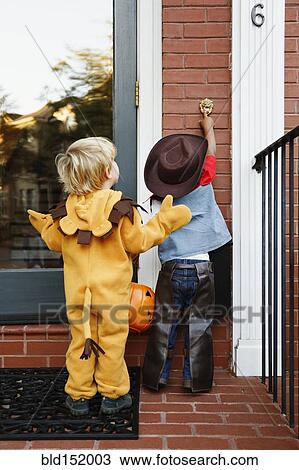 Stock Image - Boys in costumes trick or treating together on Halloween. Fotosearch
