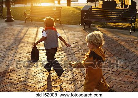 Stock Photo - Boys playing in costumes on sidewalk. Fotosearch