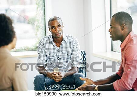 Stock Image - Business people talking in office lobby. Fotosearch
