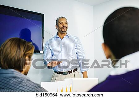 Businessman giving presentation in office meeting View Large Photo Image Picture - Businessman giving presentation in office meeting. Fotosearch