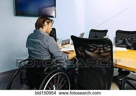 Businessman in wheelchair working at desk in office View Large Photo Image Picture - Businessman in wheelchair working at desk in office. Fotosearch