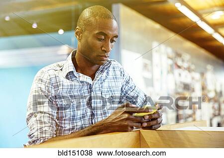 Stock Photo - Businessman using cell phone in office. Fotosearch