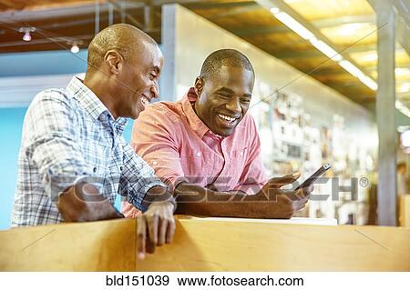 Stock Photo - Businessmen using cell phone in office. Fotosearch
