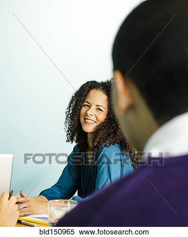 Stock Photography - Businesswoman laughing in office meeting. Fotosearch
